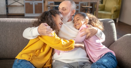 older man hugging granddaughters