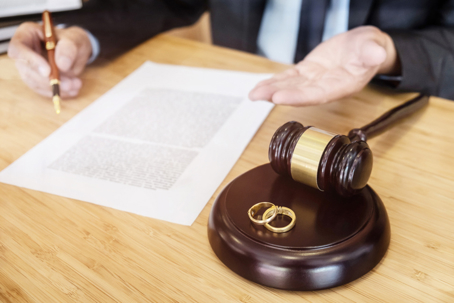 lawyer explaining document with gavel and wedding rings on desk