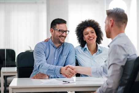 happy couple shaking hands with a lawyer
